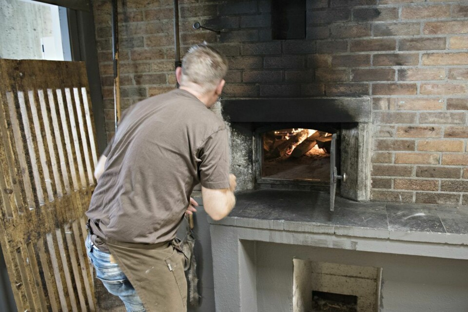 Baker Emil Lysø sjekker temperaturen i steinovnen. Ovnen er i drift hver dag, hele uken.