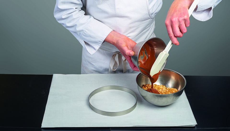 CRUMBLESJEKS: Bland den smeltede kuvertyrsjokoladen
(40 °C) med crumblen, risen og pralinen (crumblekjeks).