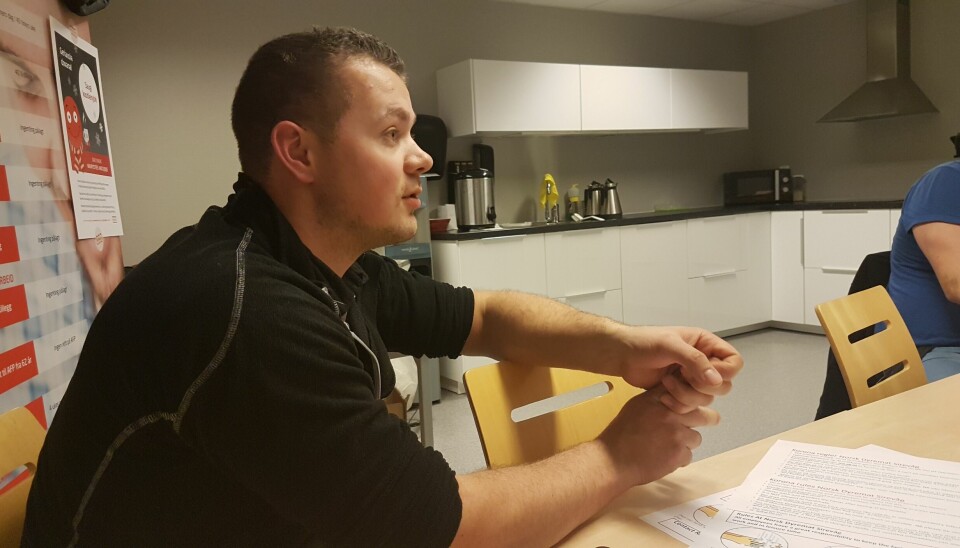 Erik Stangeland, som jobber i NNN Rogaland, sitter ved et bord og snakker med ansatte på en arbeidsplass.