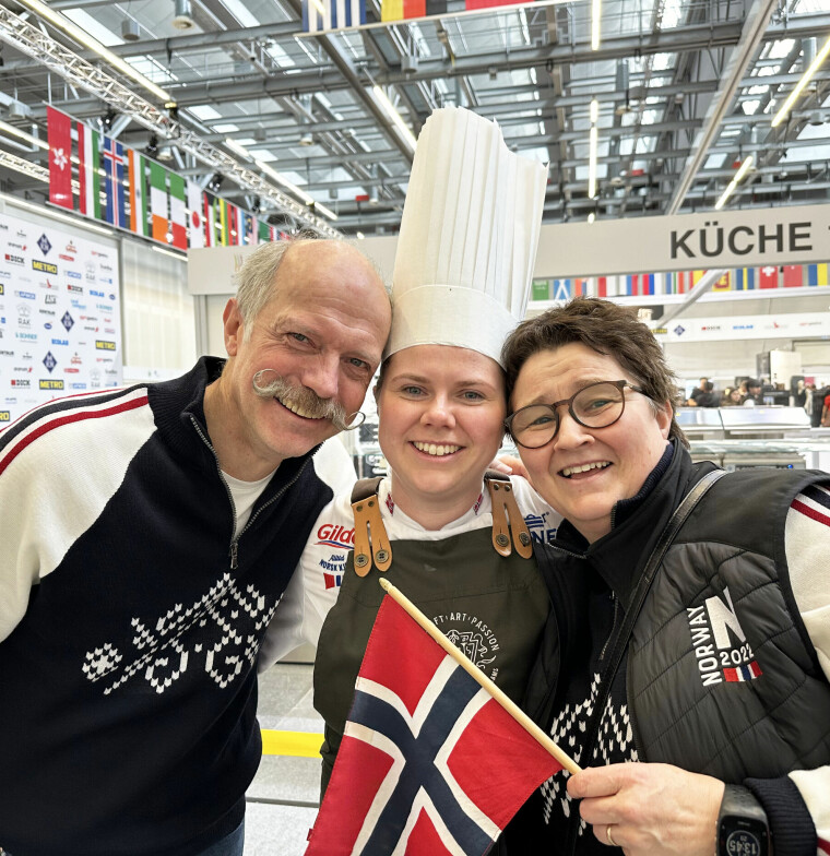 Far og mor med datteren i midten med kokkelue og norsk flagg.