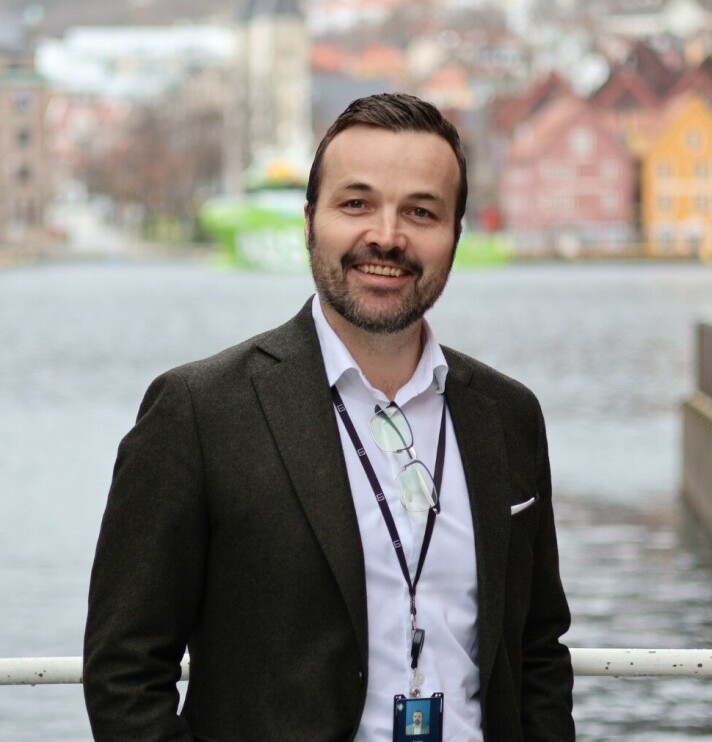 Jøran Totland Stangervåg er ansatt som ny salgs- og markedsdirektør hos Norgesmøllene. Mann i svart dressjakke og hvit skjorte med bryggen i Bergen i bakgrunnen.
