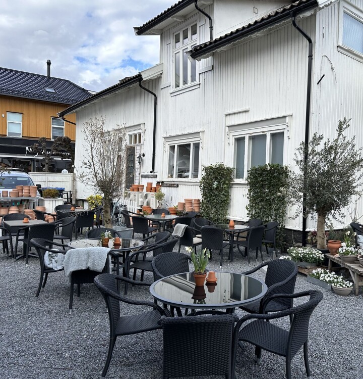 I hagen er det etablert en stor uteservering med over 100 sitteplasser. Nå har bakeriet også søkt skjenkebevilling. Sittegrupper utendørs med hvitt hus i bakgrunnen.