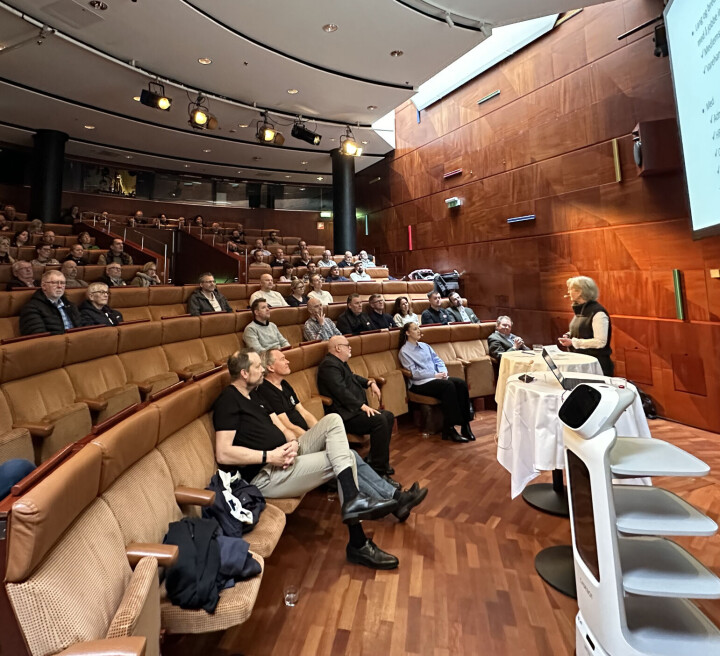 Ida Ribler presenterte seg under Din Bakers tur til Stockholm forleden. Konferansesal der person holder foredrag.