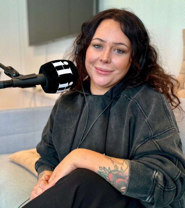 Silje Blomsø har startet podkasten «Livet med Silje» sammen med lokalavisen i byen. Dame med langt går i mørk gener med mikrofon foran seg.
