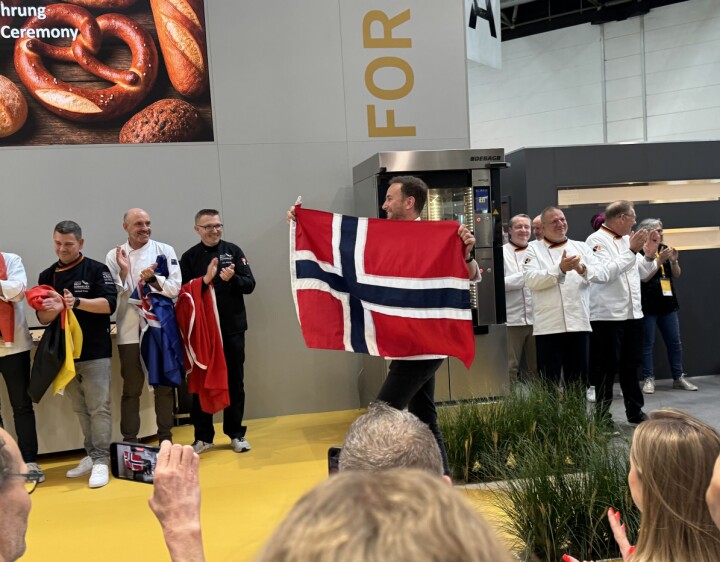 Daniel Sunzenauer entret scenen med et stort norsk flagg. Daniel Sunzenauer var en av 16 finalister i verdens første VM for brødsommelierer på iba 2025.