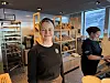 To ansatte bak bakeridisk foran hyller med brød og utsikt mot fjell