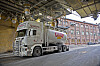 Regnbuen bulkbil lastes under industrielt påfyllingsanlegg ved fabrikkbygg.