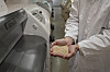 Person i laboratoriefrakk holder korn foran en Bühler-sorteringsmaskin.