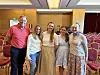 Fem personer poserer foran rader med rosa stoler i en konferansesal.