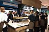 Folk står samlet i bakeriet ved disken med bakst under åpningen.