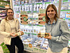 To kvinner holder Bakehuset-produkter foran en butikkhylle med brød og kampanjeplakater i Kiwi.