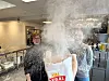 Tett melstøv fyller et arbeidslokale med en stor sekk Regal-mel i forgrunnen.