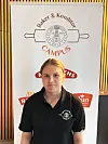 Person i svart poloskjorte står foran et banner med teksten Baker & Konditor Campus.