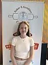Ung person står foran et banner med Baker & Konditor og flere fargede logoer.