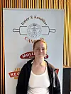 Ung kvinne står foran et banner med Baker & Konditori Camilla S og logoer for Møllerens og Regin.