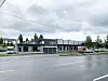 Lav bygning ved en vei under grå, overskyet himmel.