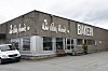 Hjørnebygning med bakeriskilt, store vinduer og varebil parkert utenfor.
