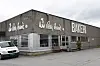 Hjørnebygning med bakeriskilt, store vinduer og varebil parkert utenfor.