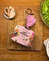 Rosa pakke med mykt sandwichbrød på en trefjøl ved siden av salat og en tallerken.
