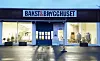 Opplyst fasade med skiltet Bakst & Brygghuset, butikkvinduer og våt brostein.
