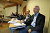 Flere menn sitter samlet ved et bord i et konferanserom.