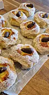 Gyllenbrune kokosstrødde bakverk med mørkt fyll på bakepapir.